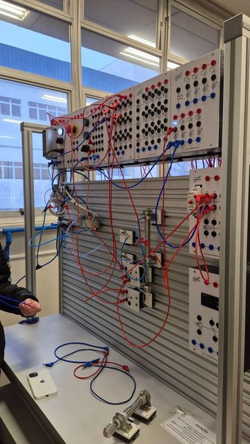 Painel de treinamento em eletropneumática do SENAI, com módulos, botoeiras e fiação colorida.